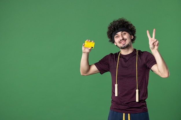 Vorderansicht junger Mann mit gelber Bankkarte auf grünem Hintergrund Modell Yoga Gesundheit Workout Lifestyle Sport Fitnessstudio Geld