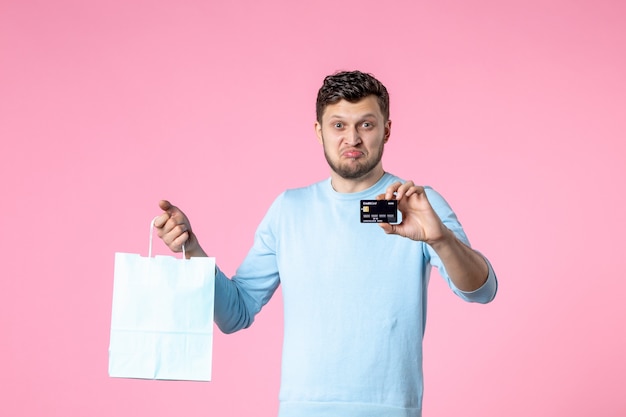 Vorderansicht junger Mann mit Geschenk und schwarzer Bankkarte auf rosa Hintergrund Gleichheit Heiratsdatum Frauentag März Liebesspaß sinnlicher Park