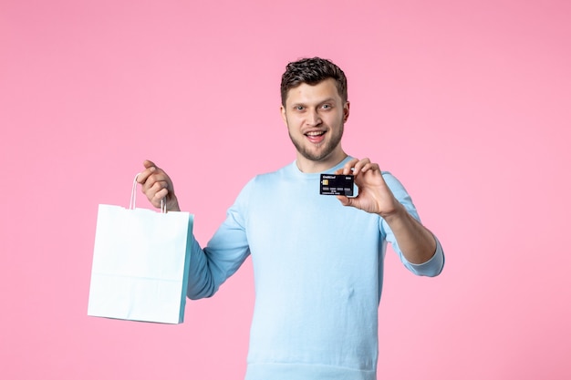 Vorderansicht junger Mann mit Geschenk und schwarzer Bankkarte auf rosa Hintergrund Gleichheit Heiratsdatum Frauentag März weiblicher Spaß sinnlicher Park