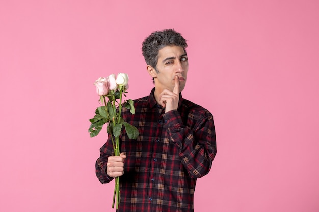 Vorderansicht junger Mann mit schönen rosa Rosen auf rosa Wand