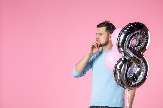 Vorderansicht junger Mann mit süßen Luftballons als Marsch auf rosa Hintergrund Liebe weiblicher Frauentag Ehegleichheitspark sinnlicher Spaß