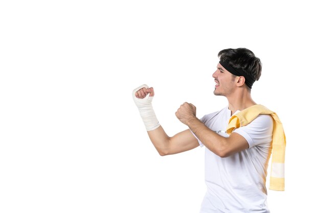 Vorderansicht junger Mann mit Verband an seiner verletzten Hand auf weißem Hintergrund Athlet Fitness-Studio Diät Sport Schmerzen Verletzung Körper fit Lebensstil