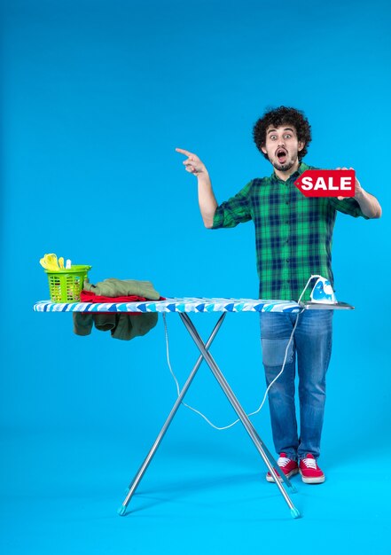 Vorderansicht junger Mann mit Verkauf schreiben auf blauem Hintergrund menschliche Waschmaschine Farbe Haus sauber einkaufen