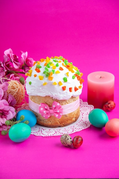 Vorderansicht köstliche Sahnetorte mit farbigen Eiern und Kerze auf rosa Hintergrund Zuckerkuchentorte süßes Dessert bunt verzierte Frühlingsferien