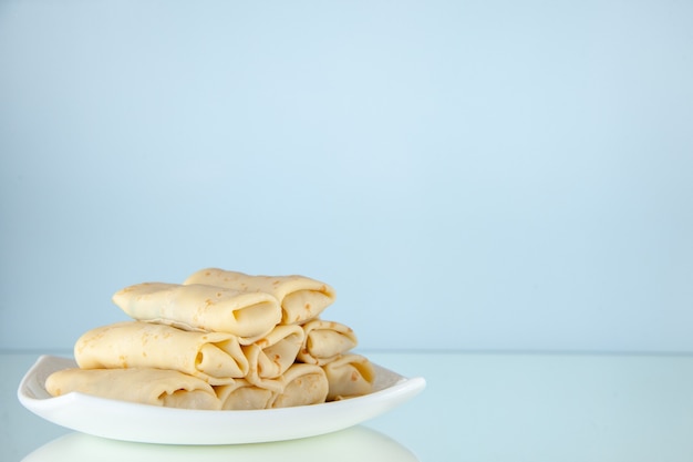 Vorderansicht köstliche süße Pfannkuchen gerollt in der Platte auf hellem Hintergrund Frühstücksmahlzeit Zuckermilchnahrung Morgenkuchenfarbe