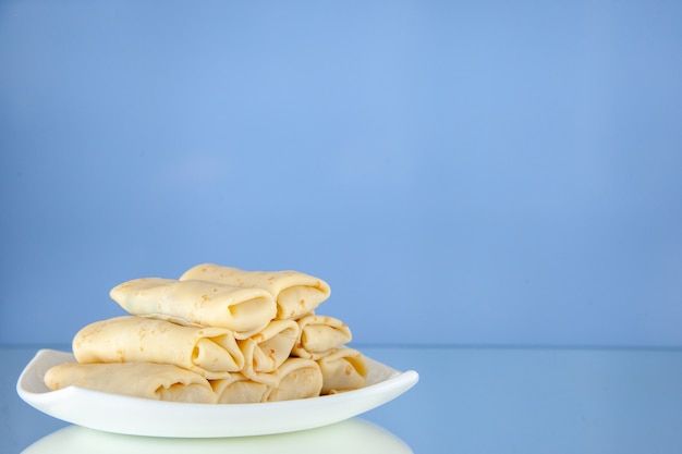 Vorderansicht köstliche süße Pfannkuchen gerollt in der Platte auf hellem Hintergrund Frühstücksmahlzeit Zuckermilchnahrung Morgenkuchenfarbe