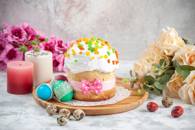 Vorderansicht köstlicher Osterkuchen mit getrockneten Früchten und farbigen Eiern auf weißem Hintergrund Konzept Frühling bunt verzierte Kuchen Dessertfarbe