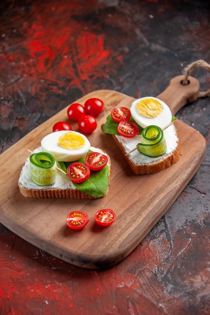 Vorderansicht leckere Eiersandwiches mit roten Tomaten auf Schneidebrett dunkelroter Hintergrund Mittagessen Toast Snack Essen Brot Mahlzeit Burger