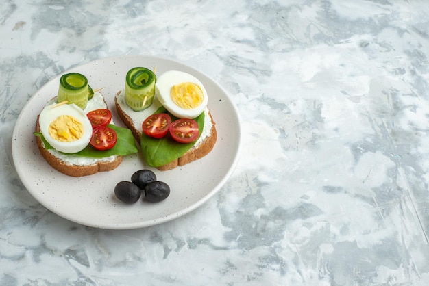 Vorderansicht leckere Eiersandwiches mit Tomaten in der Platte weiße Oberfläche Hintergrund Mittagessen Sandwich Brot Burger Gesundheit Diät Mahlzeit