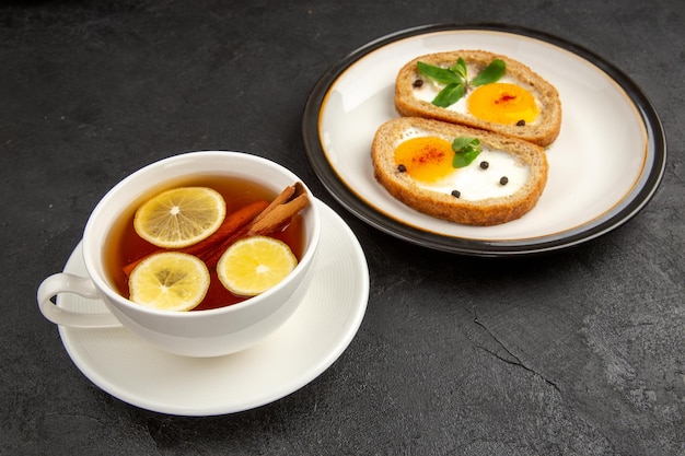 Vorderansicht leckere Eiertoasts mit Tasse Tee auf dunklem Hintergrund Mahlzeit Brot Omelette Essen Mittagessen Morgen Frühstück Tee