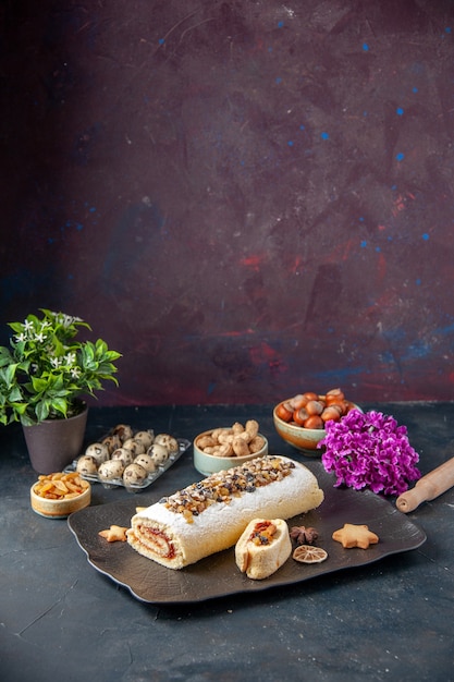 Vorderansicht leckere Keksrolle mit Nüssen auf dunklem Hintergrund Kuchen Keks Kuchen Dessert Tee Zuckerteig süße Fruchtblumen