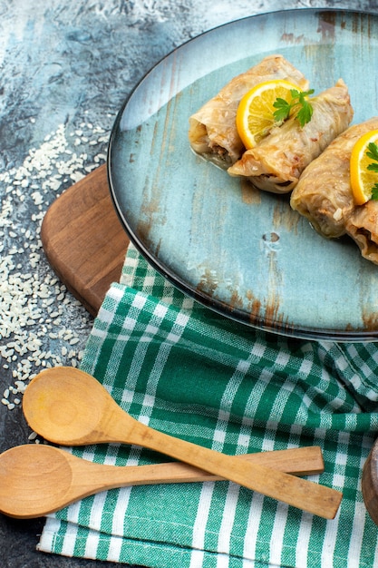 Vorderansicht leckere Kohldolma mit Zitronenscheiben und Gewürzen auf grauem Hintergrund Küche Abendessen Eisfarbe Mahlzeit Brot Essen Kalorien