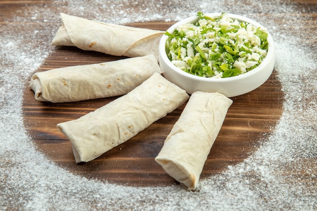 Vorderansicht leckere Pitas mit Grün um Mehl auf braunem Hintergrund Fleisch Ei backen Teig Mahlzeit Öl Kuchen Kuchen Gebäck kochen