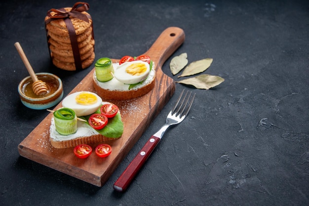 Vorderansicht leckere Sandwiches mit Tomaten und Eiern auf Schneidebrett dunkler Hintergrund Toastbrot Snack Burger Sandwich Mittagessen Essen