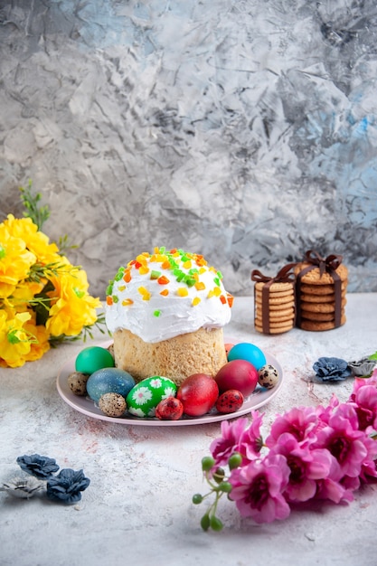Vorderansicht leckerer Osterkuchen mit farbigen Eiern im Teller auf weißer Oberfläche Frühlingstorte verzierte Ostern bunte süße Desserts