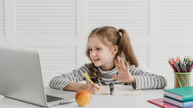 Foto vorderansicht mädchen lernen und wellen aus online-klassen