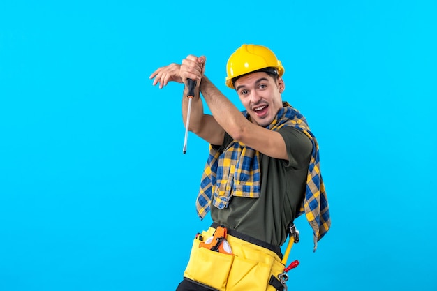 Vorderansicht männlicher Baumeister in Helm mit Schraubendreher auf blauem Hintergrund flache Architektur Haus Job Bauarbeiter Konstrukteur