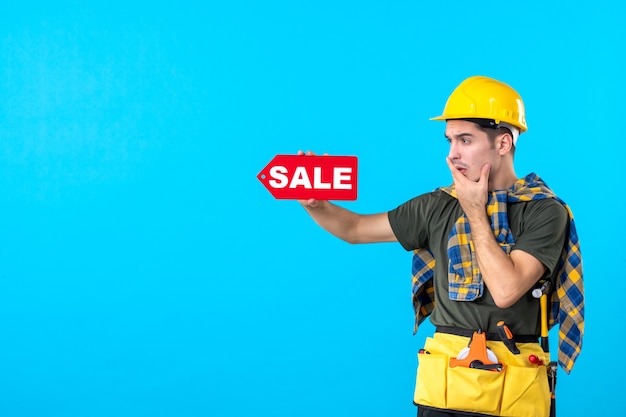 Vorderansicht männlicher Baumeister mit Verkaufsschreiben auf blauem Hintergrund flache Architektur Konstrukteur Arbeiter Gebäude Immobilienfarbe