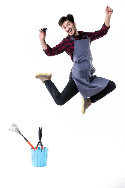 Foto vorderansicht männlicher gärtner mit bankkarte im sprung auf weißem hintergrund arbeit garten job blume boden uniform geld boden