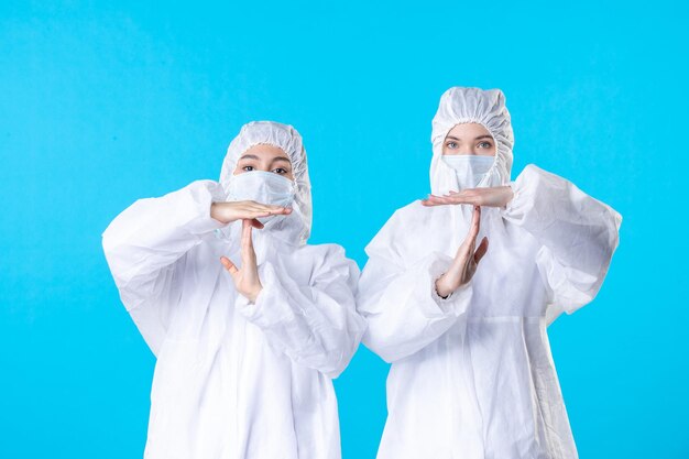 Vorderansicht Ärztinnen in Schutzanzügen und Maske auf blauem Hintergrund Farbe Virus Pandemie Krankenhaus Gesundheitswissenschaft Covid-