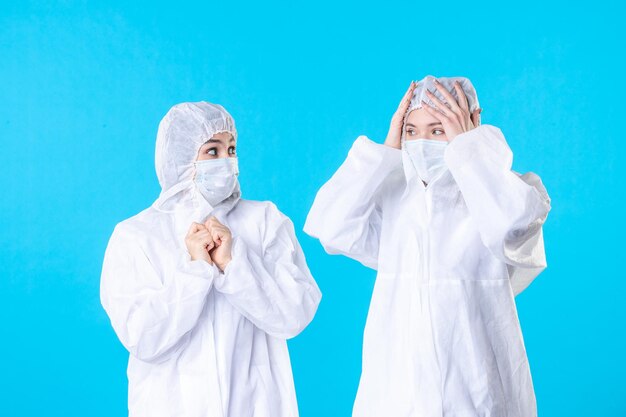 Vorderansicht Ärztinnen in Schutzanzügen und Maske auf blauem Hintergrund Viruspandemie Krankenhaus Wissenschaft Covid-Farbe