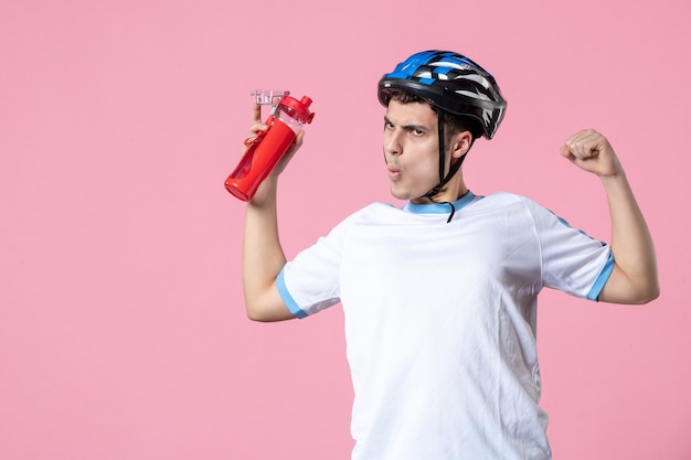 Vorderansicht starker männlicher Athlet in Sportkleidung mit Helm und Flasche Wasser