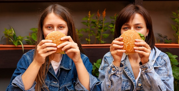 Foto vorderansicht von frauen, die ihre gesichter mit burgern bedecken