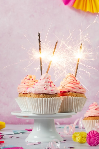 Vorderansicht von Geburtstagskleinen kuchen mit Zuckerglasur und Wunderkerzen