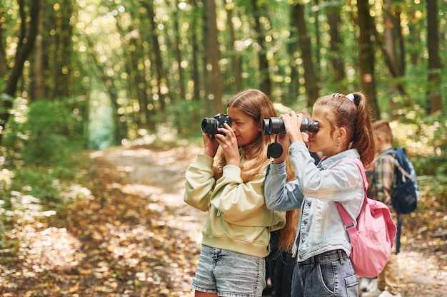 Vorderansicht von Kindern, die im Sommer tagsüber zusammen im grünen Wald sind