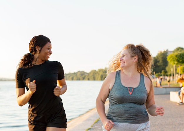 Foto vorderansicht von smiley-freundinnen, die zusammen joggen