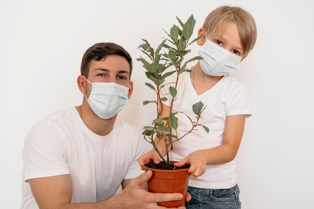 Foto vorderansicht von vater und sohn, die topf der pflanze halten