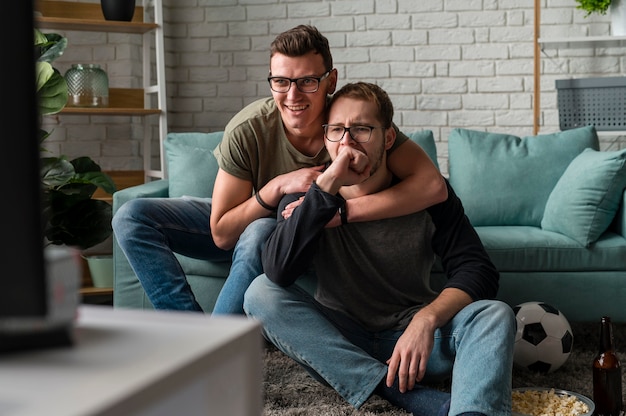 Foto vorderansicht von zwei männlichen freunden, die zusammen sport im fernsehen schauen