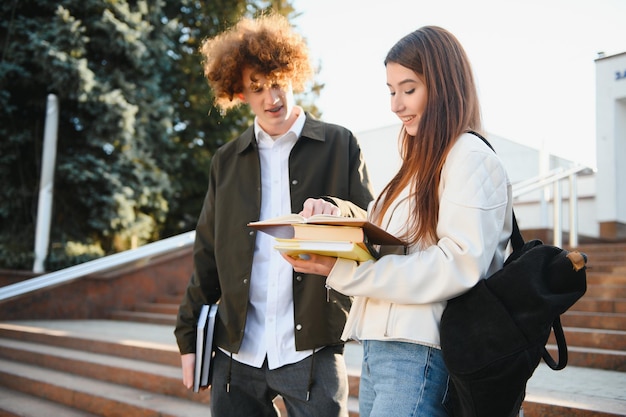Vorderansicht von zwei Studenten, die auf einem Universitätscampus spazieren und sich unterhalten