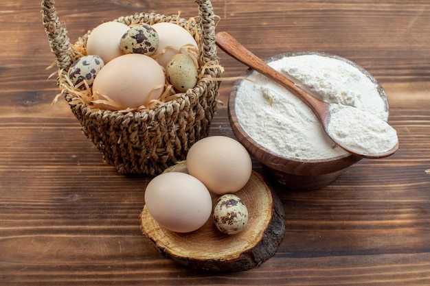 Vorderansicht Weißmehl mit Eiern auf braunem Holzschreibtisch Mahlzeit Pie Keks Ofenkuchen backen Teig kochen