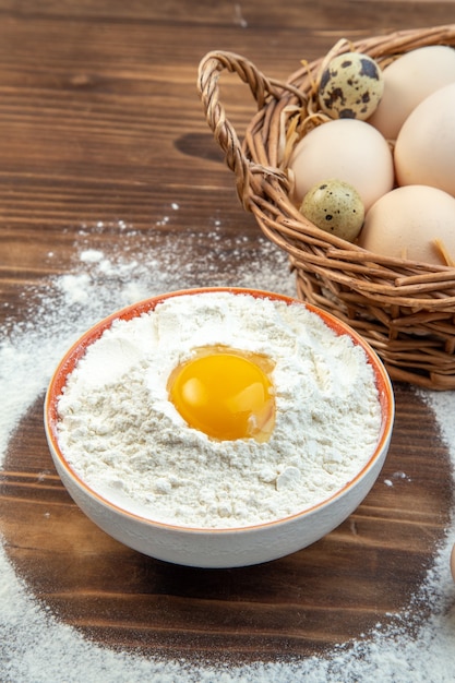 Vorderansicht Weißmehl mit Eiern im Korb auf braunem Hintergrund Lebensmittelteigkuchen backen Farbe Gebäck roher Küchenkuchen