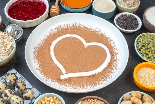 Foto vorderansicht weißmehl mit nüssen samen getreide rosinen und gelee auf dunklem hintergrund kuchen frühstück essen kuchen staub backen farbe teig herz