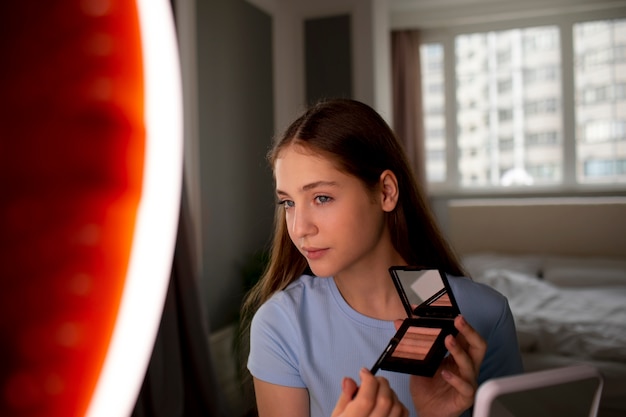 Foto vorderansichtmädchen, das make-up anlegt