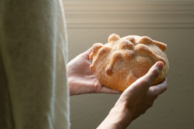 Vordere Nahaufnahme einer Person, die Pan de Muerto hält, selektiver Fokus und Kopierraum