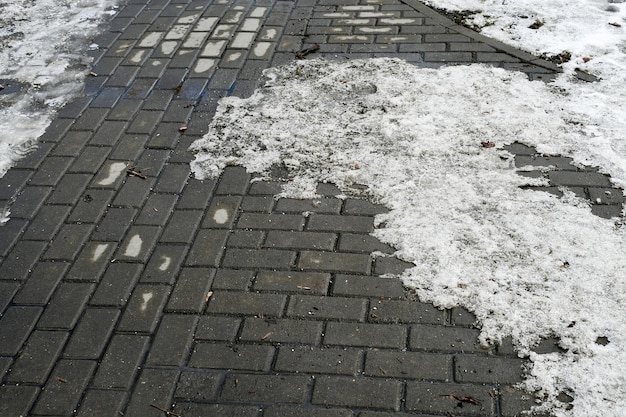 Vorfrühling Schneereste auf der Gasse des Stadtplatzes Die Gasse ist gefliest