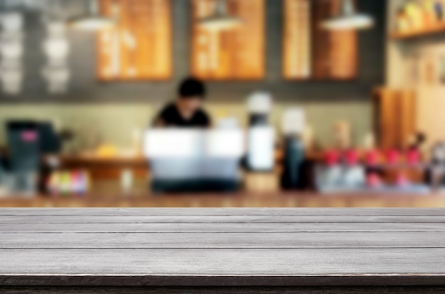 Vorgewählter Fokus leeren braunen Holztisch- und Kaffeestube oder Restaurantunschärfehintergrund