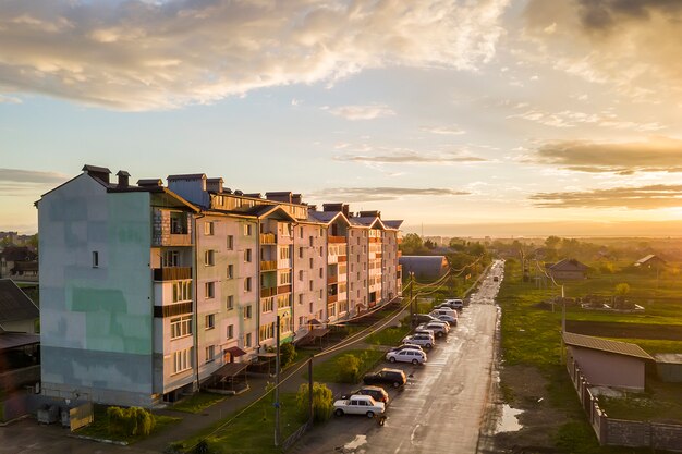 Vorortlandschaft mit Wohngebäude und Parkautos entlang schlechter Straße