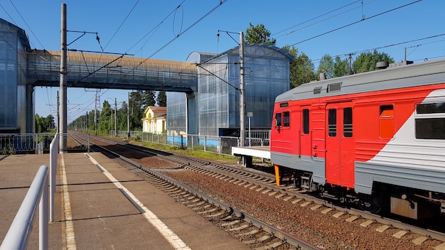 Vorortszug kommt in Station am Sommer am sonnigen Tag an. Bahnsteig mit Zug unterwegs.