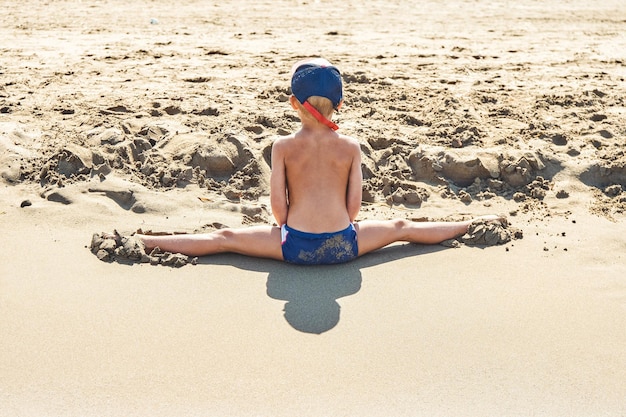 Vorschüler macht Beine auf weichem Sand der Küste