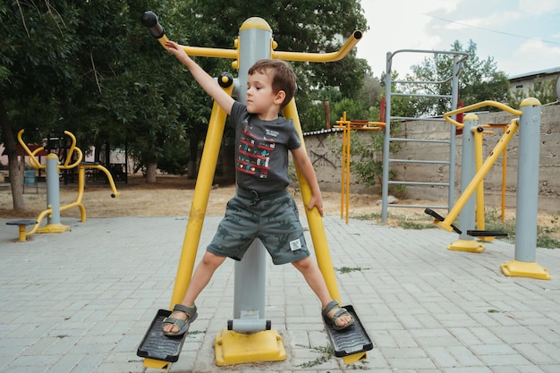 Vorschuljunge spielt im Sommer auf Simulatoren auf dem Spielplatz