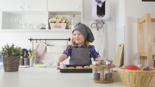 Vorschulmädchen Bäcker hält ein Backblech mit Keksen hautnah