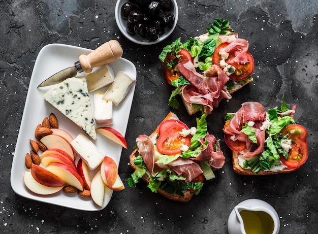 Vorspeisentisch Gorgonzola-Brie-Käse, getrocknete Oliven und Prosciutto-Tomaten-Sandwiches mit grünem Salat