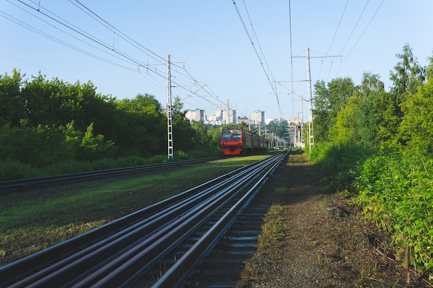 Vorstadtlandschaft am Morgen mit elektrischer S-Bahn, die sich aus der Stadt am Horizont bewegt