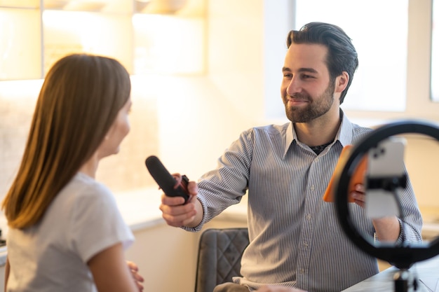 Vorstellungsgespräch im Studio. Junger bärtiger Journalist interviewt eine langhaarige Frau