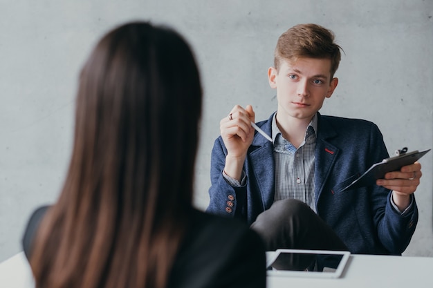 Vorstellungsgespräch. verachtungsvoller junger hr-manager, der weibliche bewerber mit skeptischem gesichtsausdruck hört.