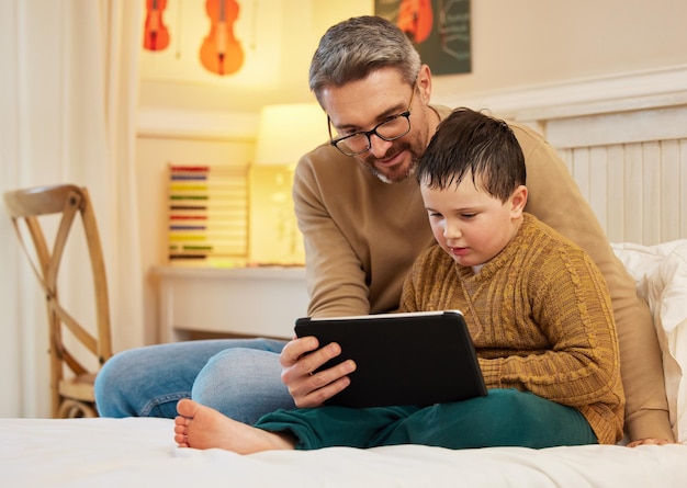 Vou deixar você assistir um último episódio antes de dormir Foto de um pai e filho usando um tablet digital juntos em um quarto em casa